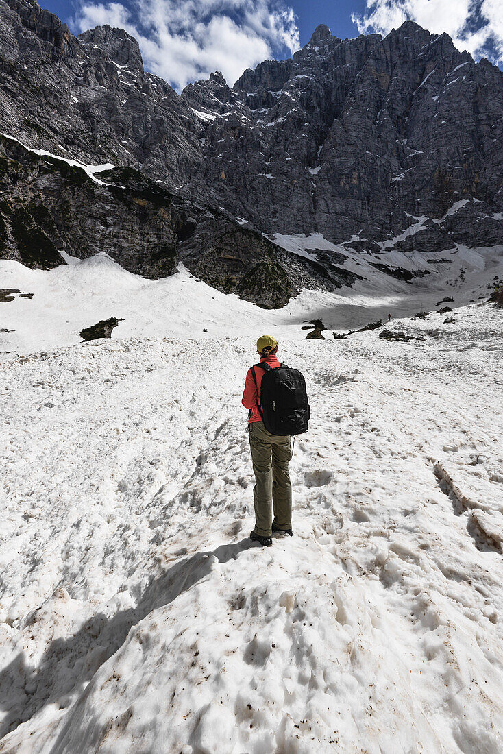 Woman hiking in the snow in front of the north face of Mount Triglav, highest peak in Slovenia, Vrata Valley, Triglav National Park, Julian Alps, Slovenia, Europe