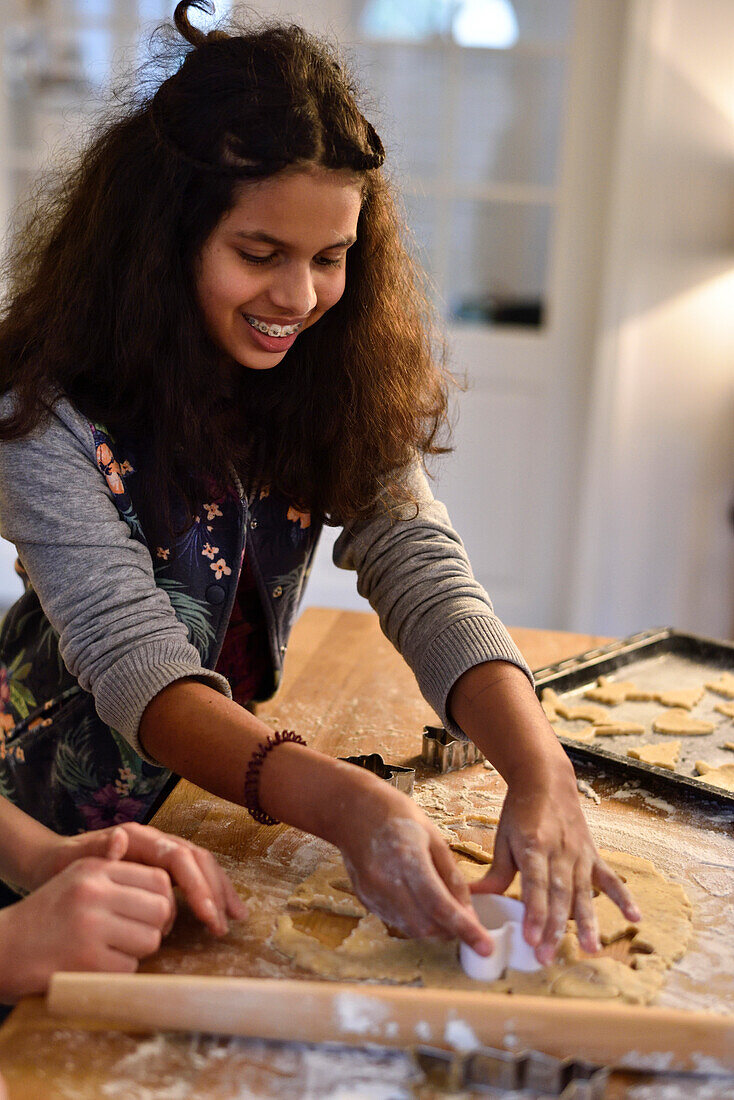 11 years old girls baking christmas cookies, cutting out dough, Hamburg, Germany