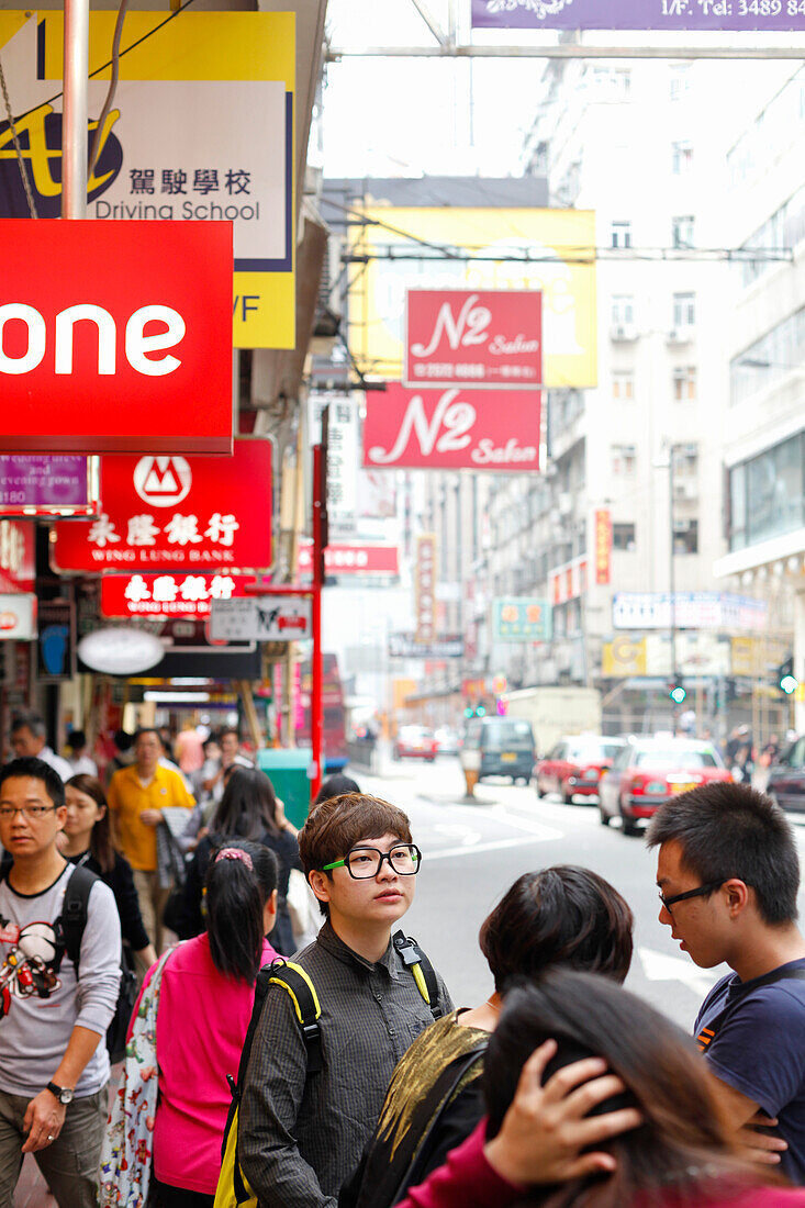 Junger Mann mit großer Brille, Hipster, Passanten auf der Straße, Bürgersteig, Einkaufsgegend Causeway Bay, Schilder, Werbung, chinesische Schriftzeichen, Straßenszene, Hongkong, China, Asien