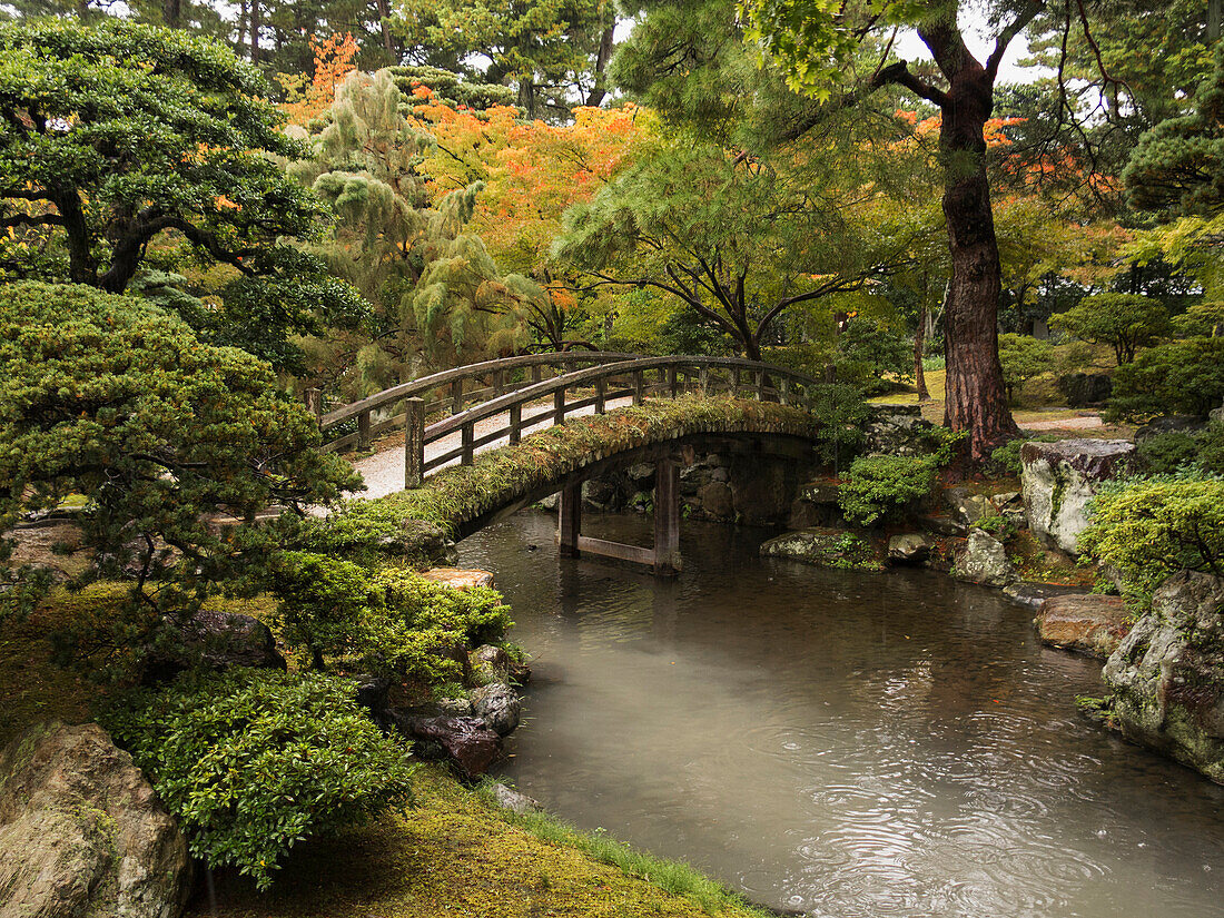 Japanese stone bridge across a stream in a park, Kyoto, Japan
