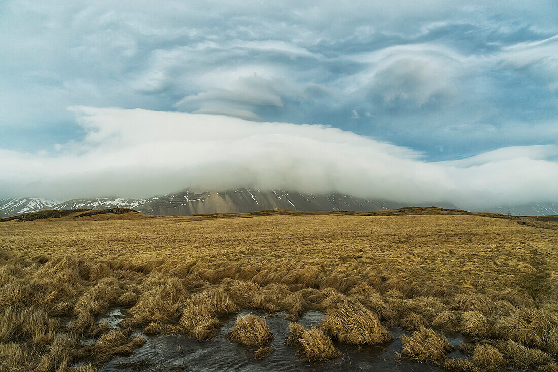 High winds create lenticular clouds in the upper atmosphere over the Eastern Fjords in Southeastern Iceland, Iceland