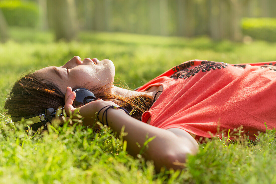 Chinese girl listening to music on the grass, Xiamen, Fujian Province, China