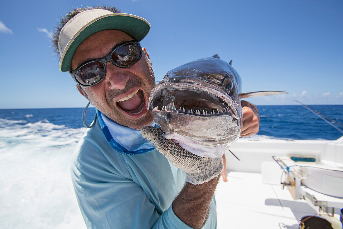 Fisherman holding a fresh caught Dogtooth Tuna Gymnosarda unicolor, Tahiti