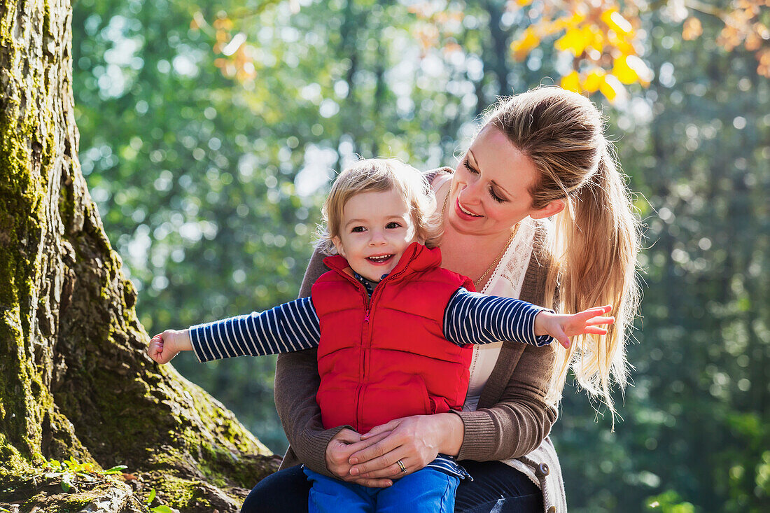 A mother holding her toddler son in a park in autumn, Langley, British Columbia, Canada