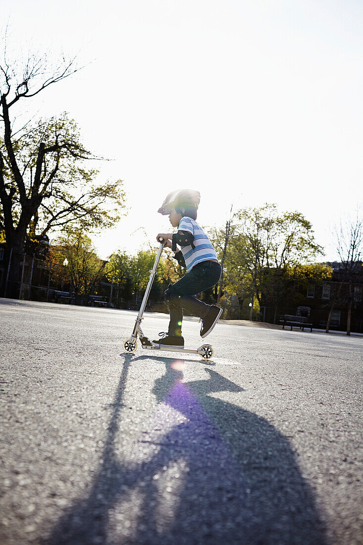 Young boy riding a 2-wheeled scooter, Montreal, Quebec, Canada