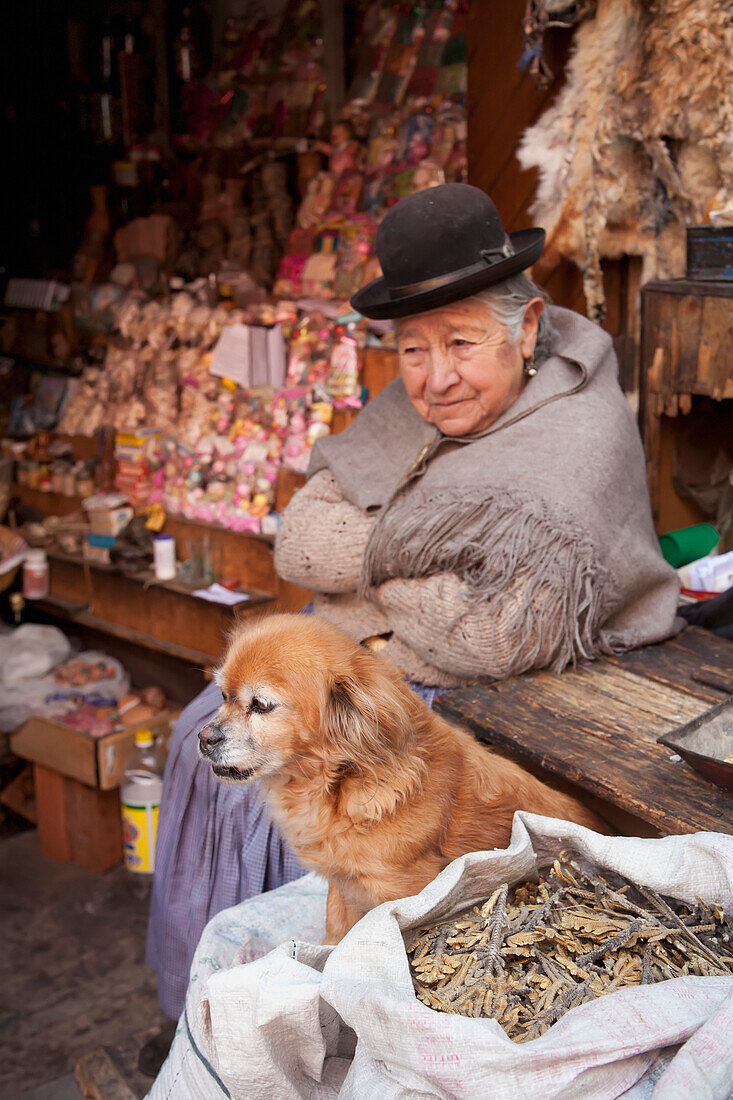 Ole Aymara Woman And Her Dog At The Mercado De Las Brujas Witches' Market On Calle Linares In La Paz., La Paz Department, Bolivia