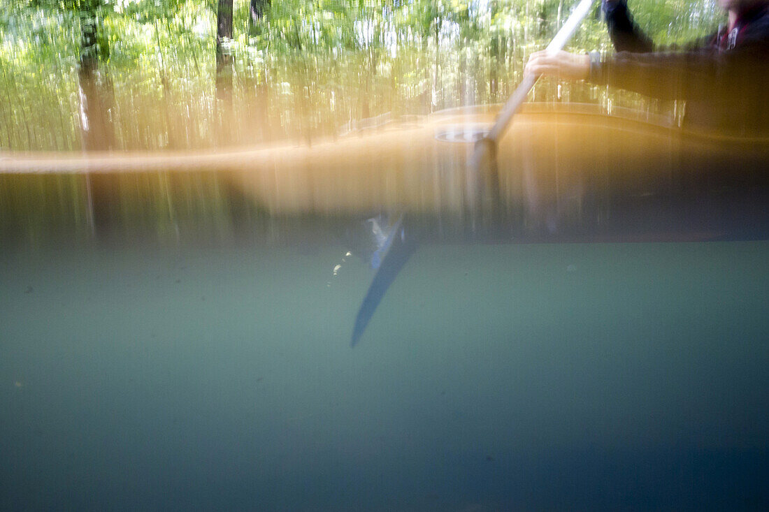Kayak tourists paddling through the Spreewald biosphere reserve. Photograph taken at level of water surface. Half above and half below the water surface, biosphere reserve, Schlepzig, Brandenburg, Germany