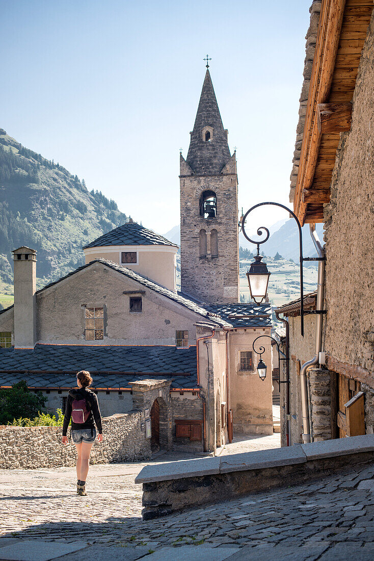 Young Adult Woman Walking Through Quaint Village, Rear View, Lanslevillard, Val Cenis Vanoise, France
