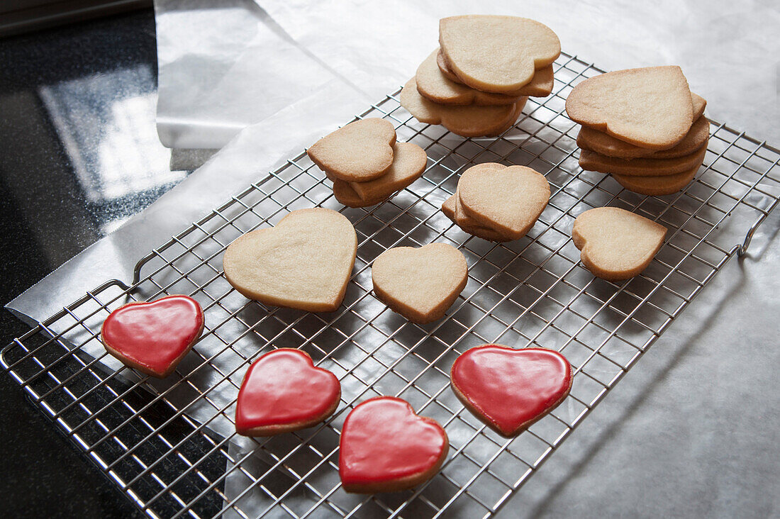 Small and Large Heart-Shaped Shortbread Cookies on Cooling Rack, Some with Red Glaze