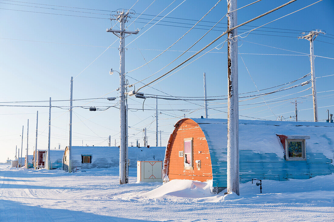 A row of powerlines stand beside Barrow Naval Base Quonset huts, Barrow, Arctic Alaska, Winter