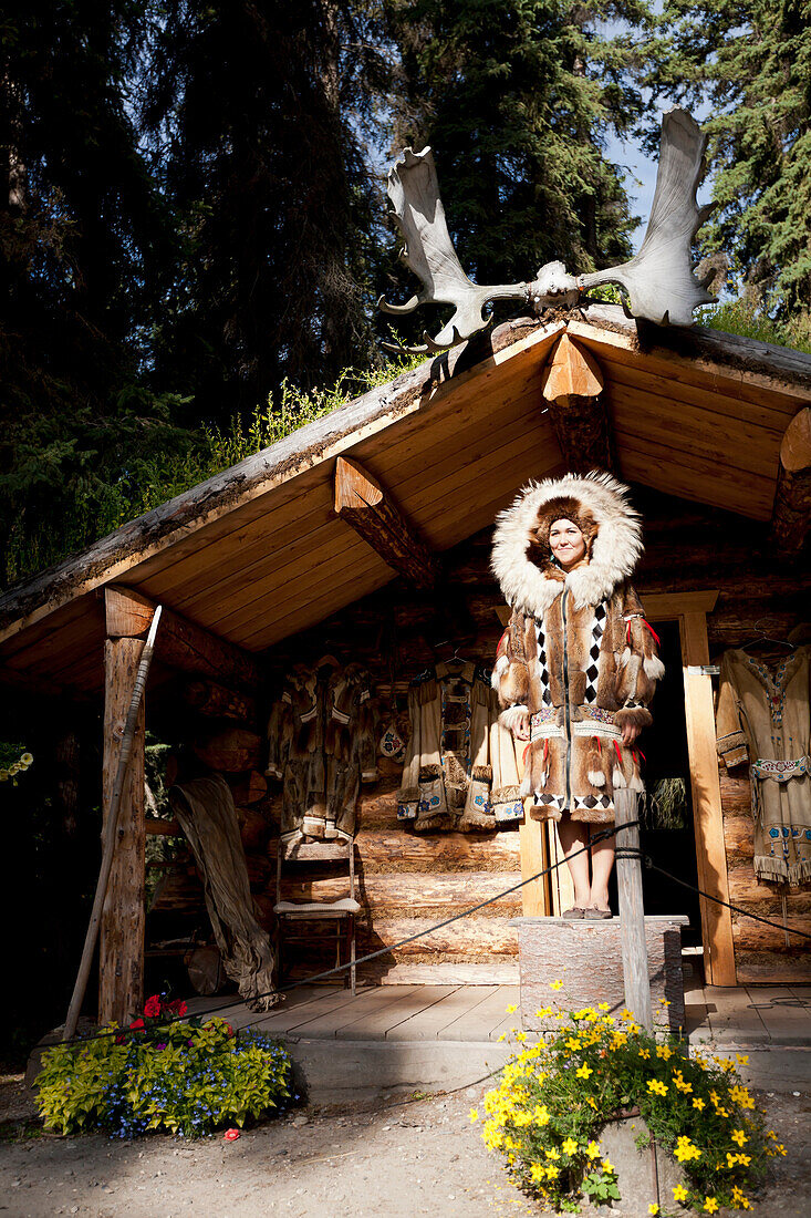 Alaskan Native Indian guide modeling a fur coat outside a cabin at an Athabascan village on the Riverboat Discovery Tour, Fairbanks, Interior Alaska, Summer
