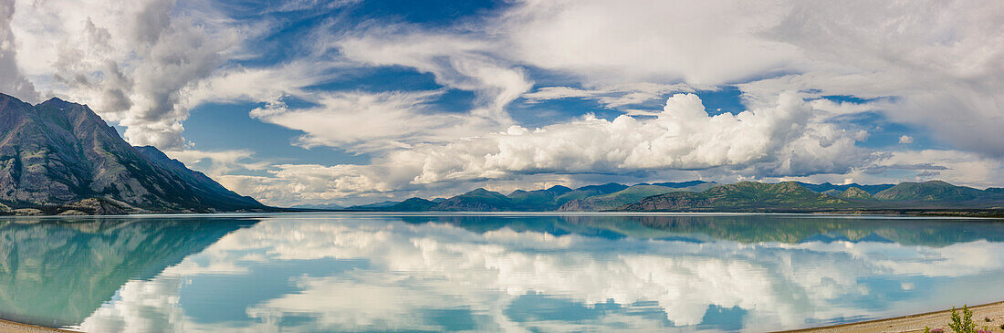 Scenic view of mountains and clouds reflecting in the calm waters of Kluane Lake, Yukon Territory, Canada, Summer