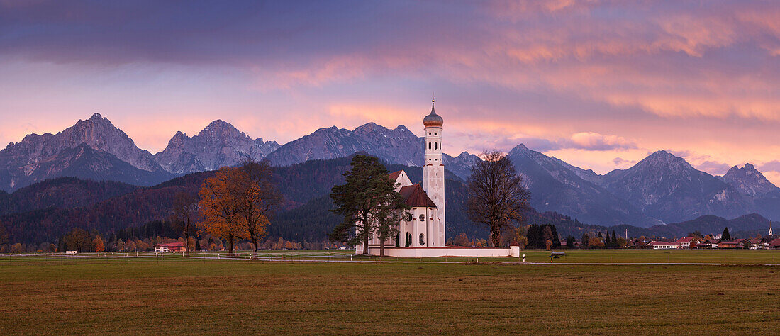 Sonnenaufgang über der barocken Kirche St. Coloman nahe Schwangau mit dem Tannheimer Gebirge im Hintergrund, Bayern, Deutschland