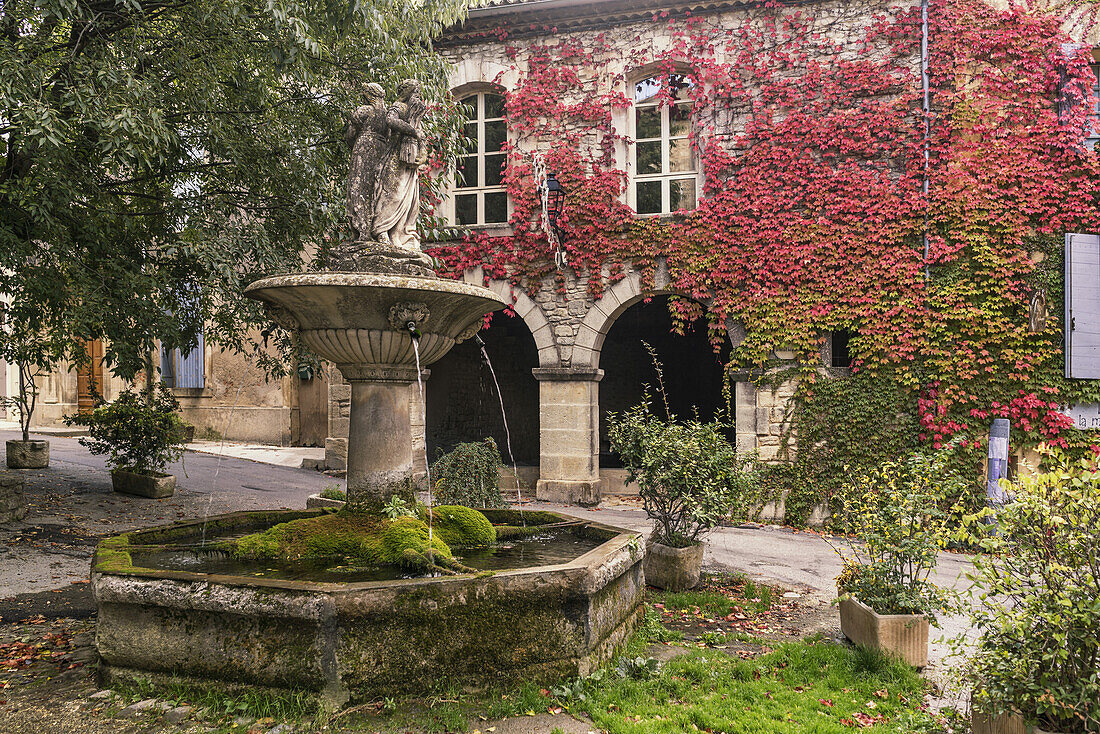 Fountain in Saignon, facade with wild wine in autumn, Provence-Alpes-Cote d’Azur, France