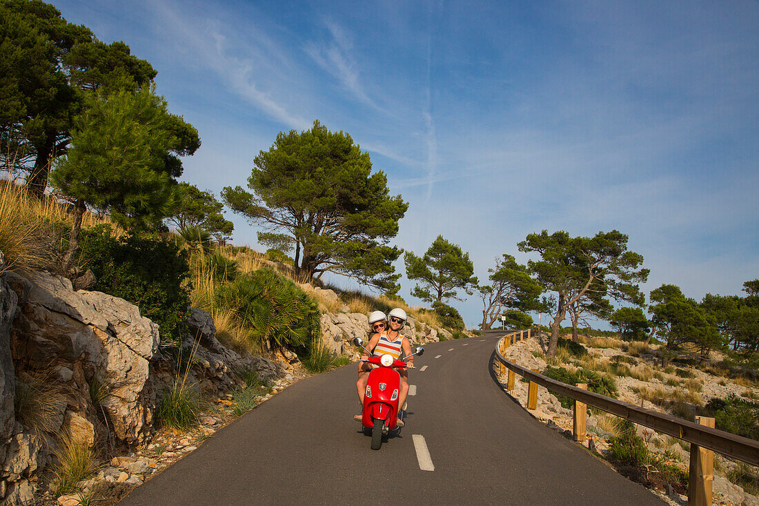 Junges Paar fährt roten Vespa Motorroller auf Straße entlang der Halbinsel Cap de Formentor, Cap de Formentor, Palma, Mallorca, Balearen, Spanien