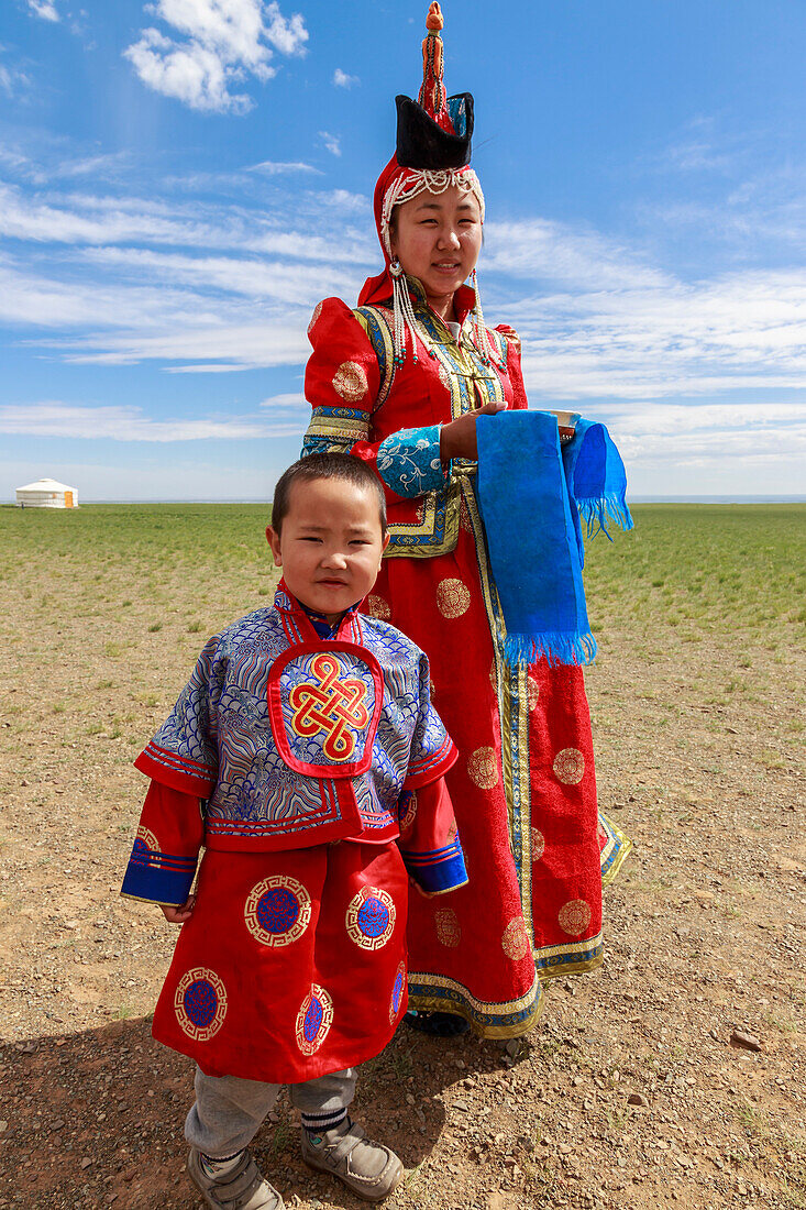 Woman and child in traditional dress deel, silver bowl for milk greeting, near ger, Gobi desert, Bulgan, Omnogov, Mongolia, Central Asia, Asia