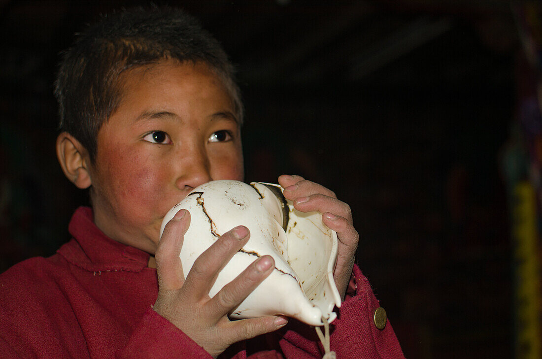 Junger Moench blaest dung kar, Muschelhorn in Dzong, Jhong, Ortschaft am Annapurna Circuit Trek mit buddhistischem Kloster, Mustang, Nepal, Himalaya, Asien