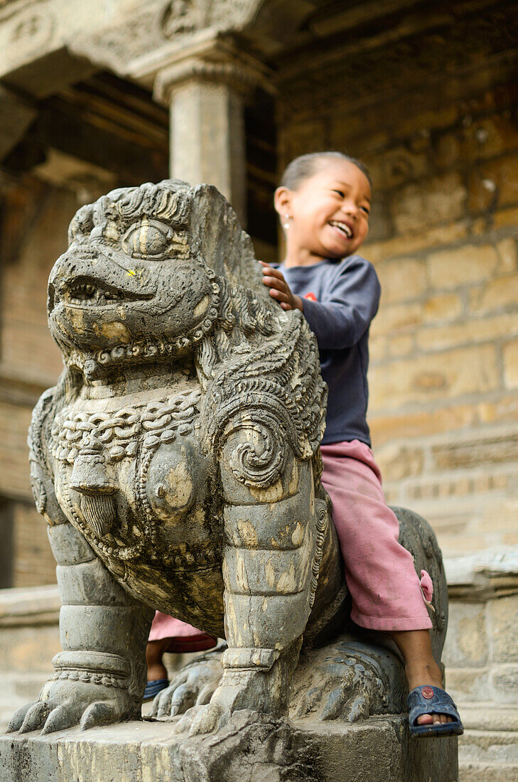 Kleines Maedchen auf Steinskulptur in Kathmandu, Nepal, Himalaya, Asien