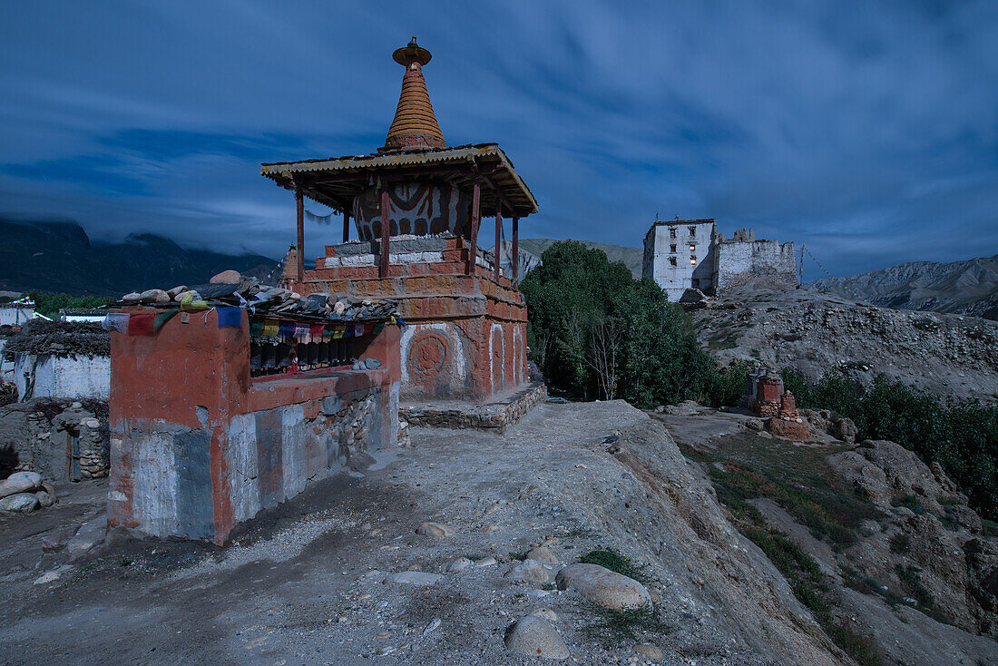 Full moon above the King's palace in white, prayer wheels, stupa and chorten in Tsarang, Charang, tibetian village with a buddhist Gompa at the Kali Gandaki valley, the deepest valley in the world, fertile fields are only possible in the high desert due t