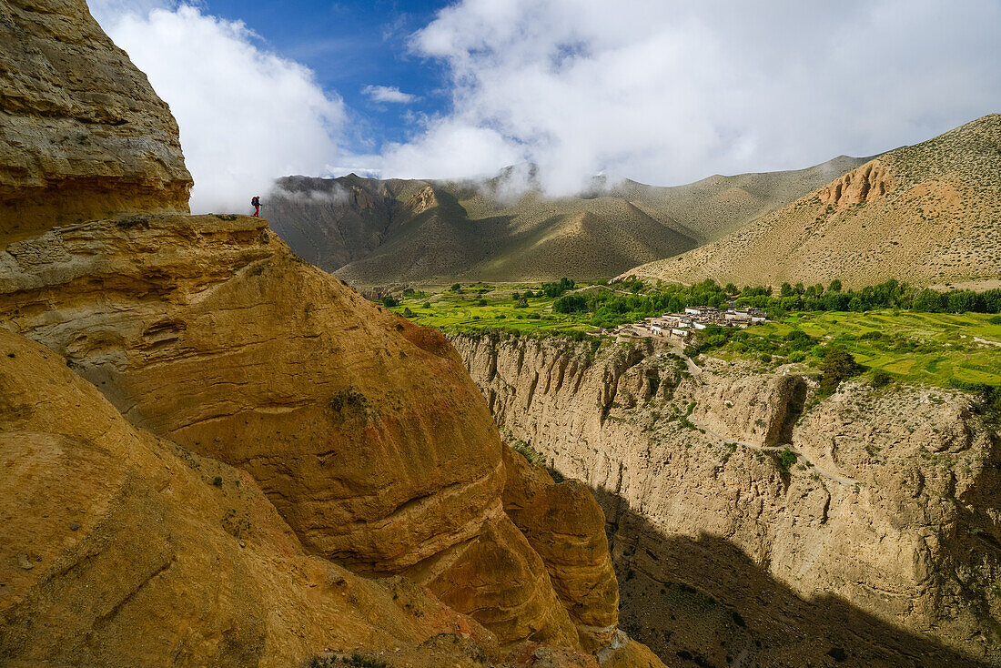 Young woman, hiker, trekker in the surreal landscape typical for Mustang in the high desert around the Kali Gandaki valley, the deepest valley in the world. Fertile fields are only possible in the high desert due to a elaborate irrigation system. In the b