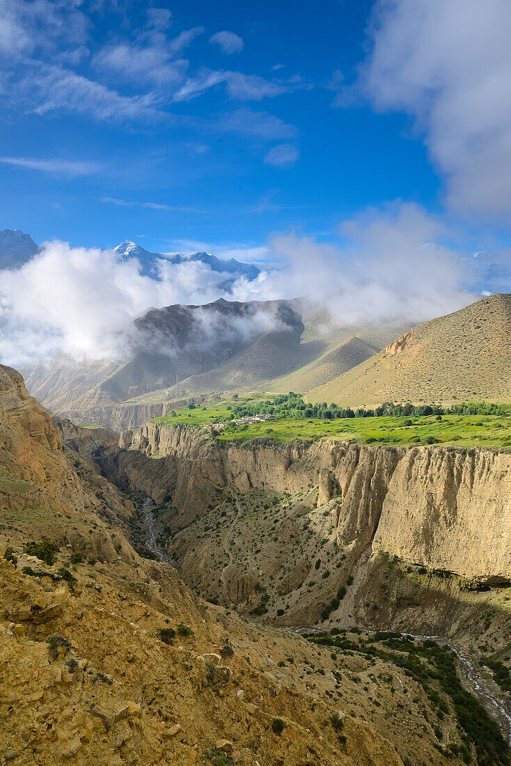 Surreal landscape typical for Mustang in the high desert around the Kali Gandaki valley, the deepest valley in the world. Fertile fields are only possible in the high desert due to a elaborate irrigation system. In the background the Gurung village Ghyaka