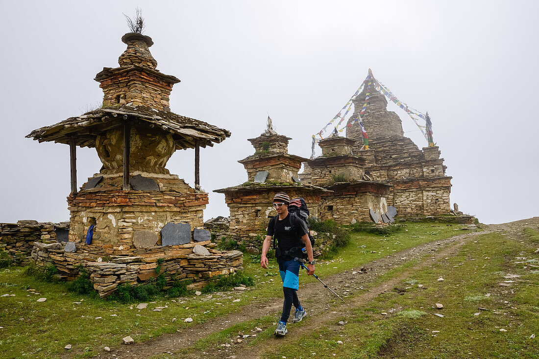Mann wandert an buddhistischen Stupas von Nar vorbei auf dem Nar Phu Trek, Nepal, Himalaya, Asien