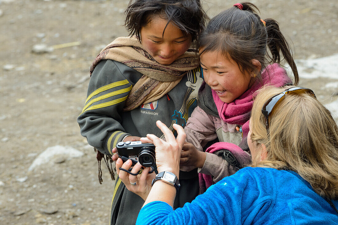 Young woman playing with small girls in Nar on the Nar Phu Trek, Nepal, Himalaya, Asia