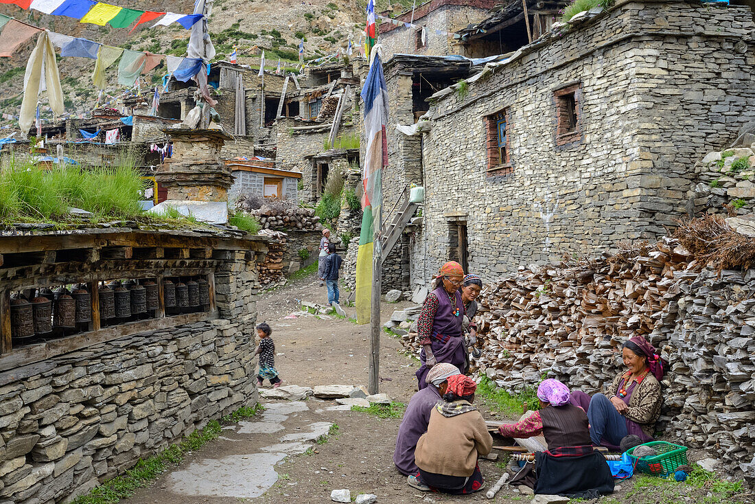 Prayer wheels, prayer flags and tibetan women in Nar on the Nar Phu Trek, Nepal, Himalaya, Asia