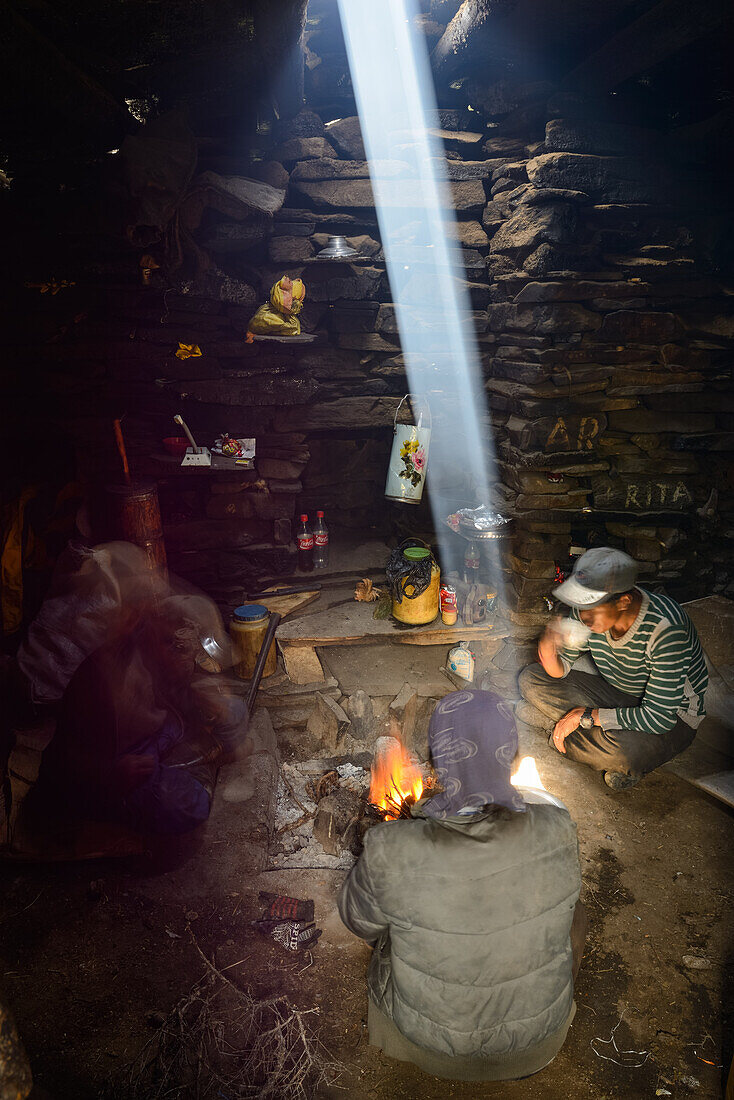 Yak shepherds from Nar in their summer residence at the camp fire, sun beam, light beam illuminates the smoke of the campfire, Nepal, Himalaya, Asia