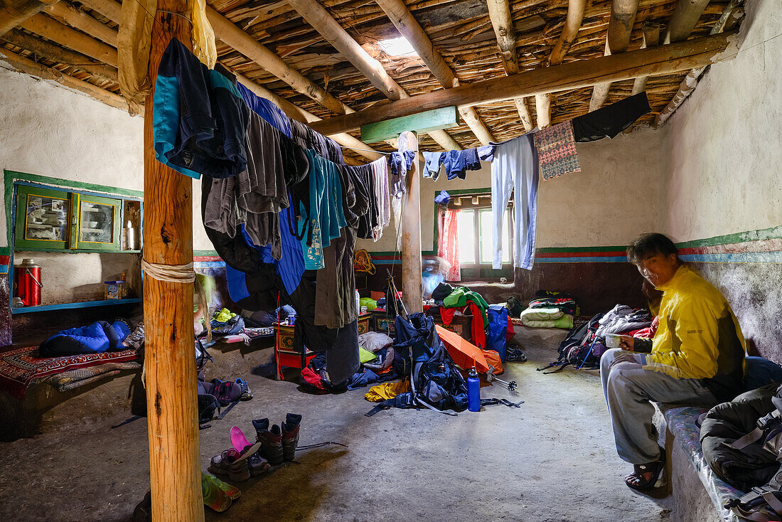 Young man is sitting inside a typical tibetan home in the living and prayer room, Tangge, tibetian village with a buddhist Gompa in the Kali Gandaki valley, the deepest valley in the world, Mustang, Nepal, Himalaya, Asia