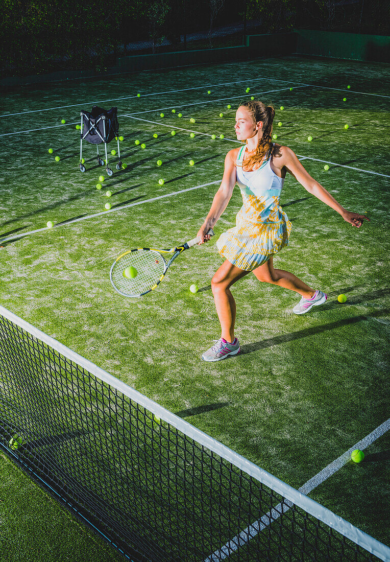 A girl on a tennis court with a racquet and numerous tennis balls, Tarifa, Cadiz, Andalusia, Spain