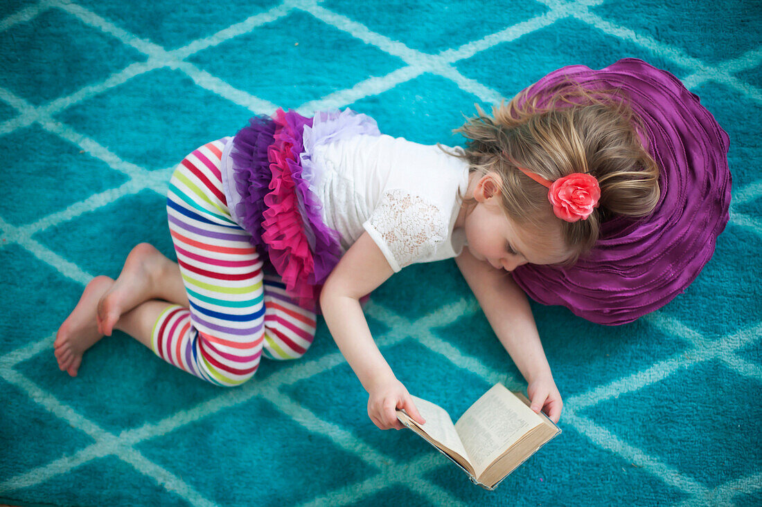 Girl reading book on floor