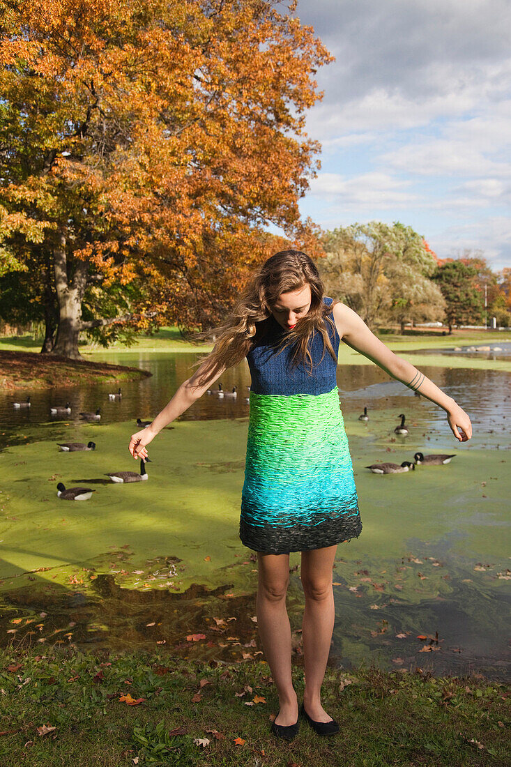 Woman wearing dress near duck pond in park