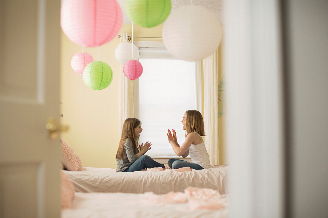 Caucasian girls playing clapping game in bedroom