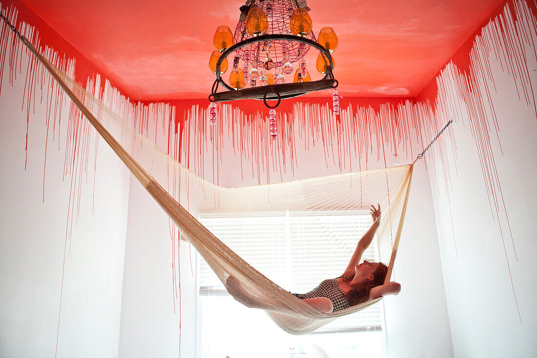 Caucasian woman laying in hammock under dripping ceiling