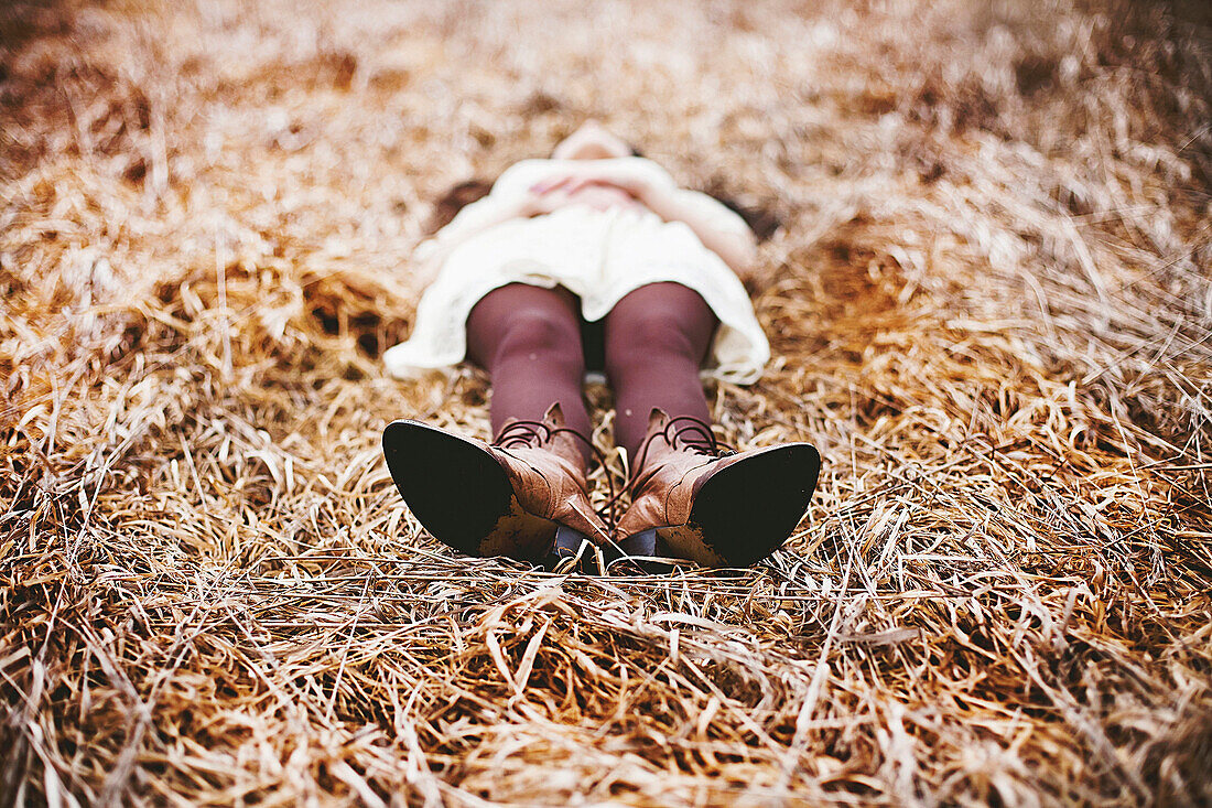 Caucasian teenage girl laying in tall grass