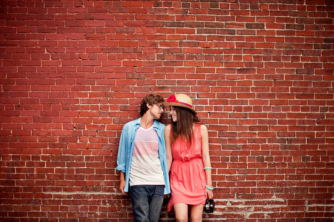 Couple leaning on brick wall