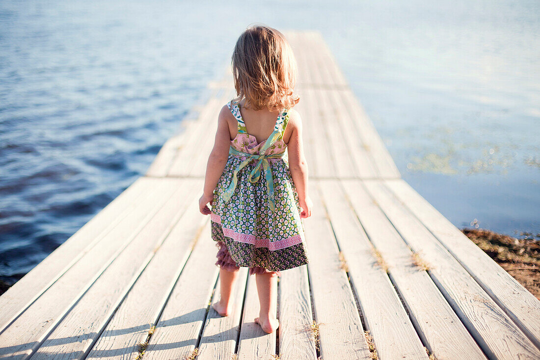 Girl walking on wooden dock over rural lake