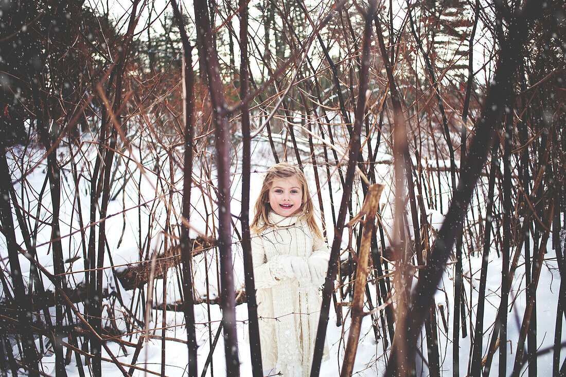 Caucasian girl playing in snowy forest