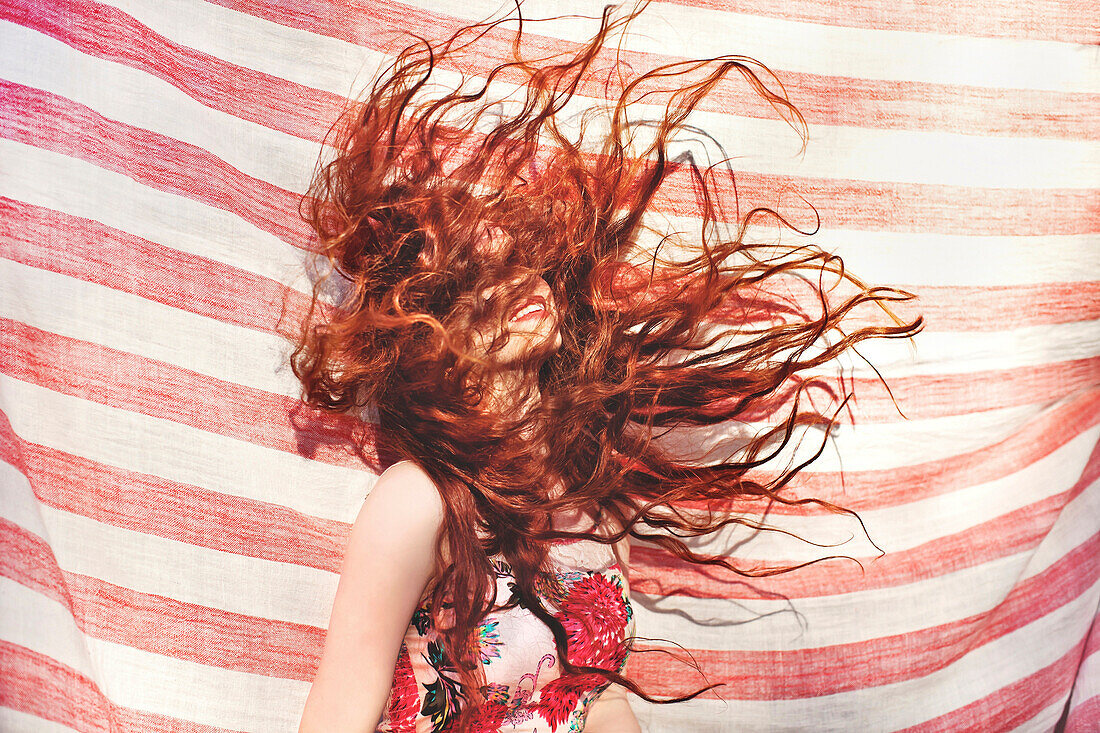 Hispanic woman tossing her hair near striped sheet