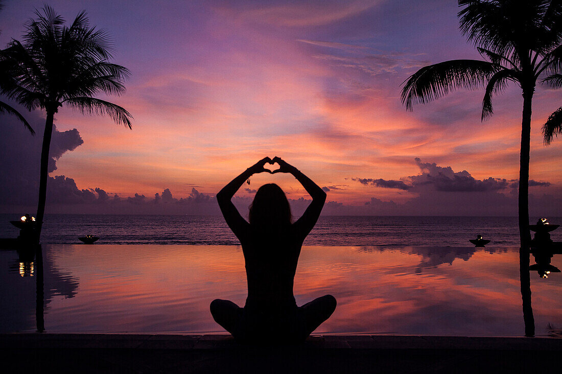 Silhouette der Frau gestikuliert Liebe in der Nähe von Schwimmbad bei Sonnenuntergang