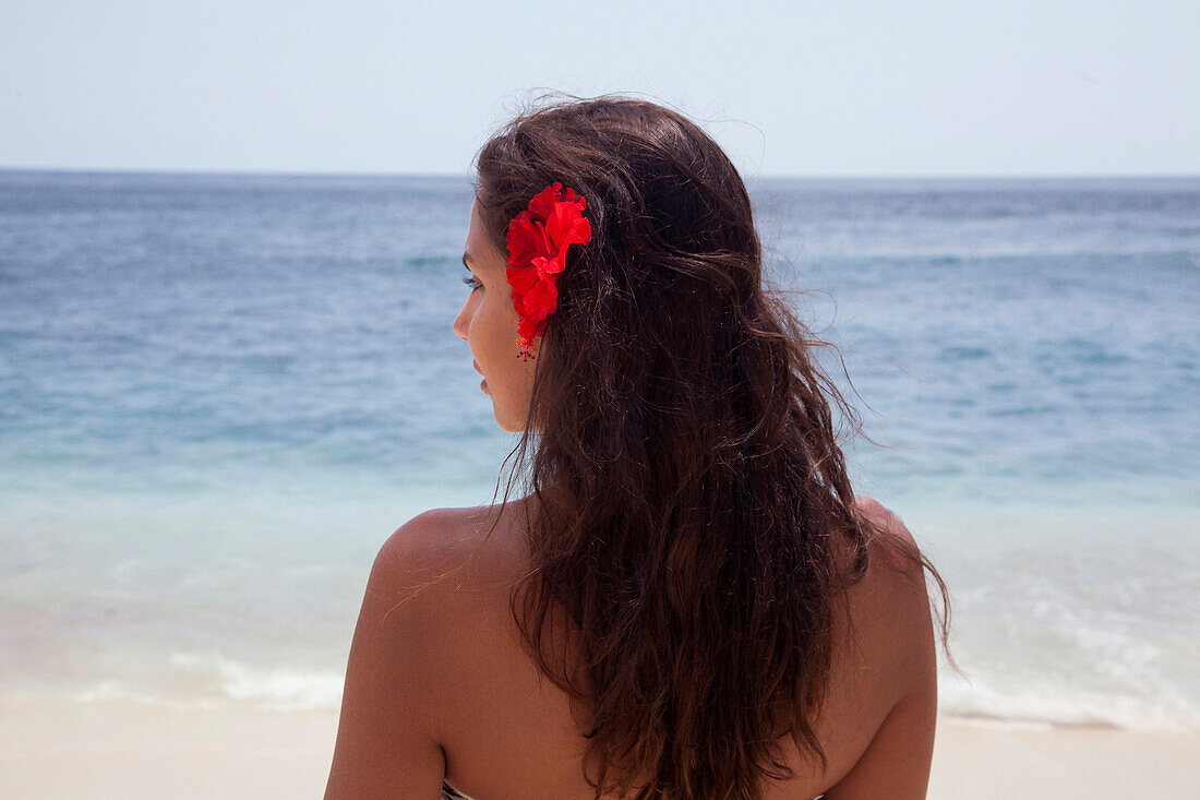 Rear view of woman wearing flower in her hair on beach