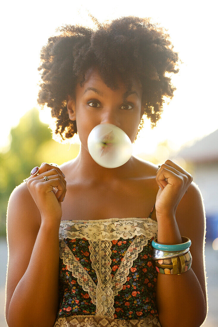Woman blowing bubble gum bubble outdoors