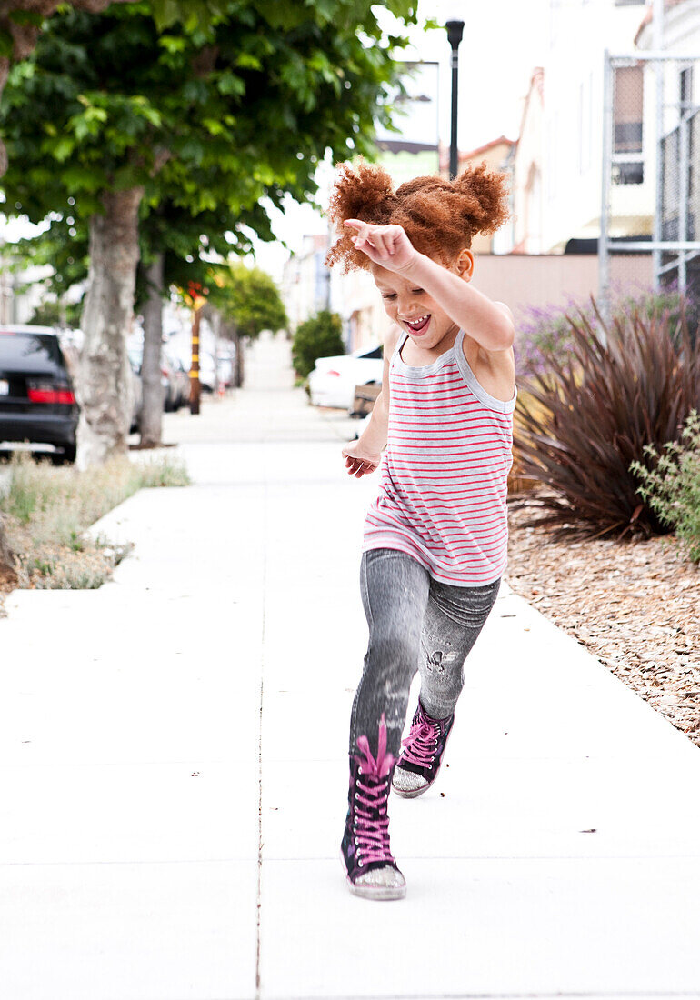 Smiling girl running on city sidewalk