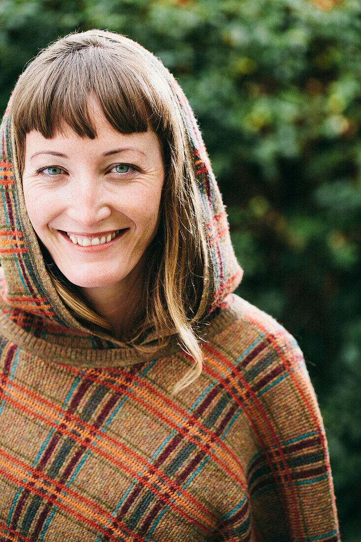 Mixed race woman wearing hood and shawl in backyard