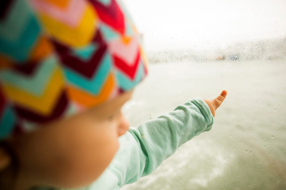 Caucasian baby girl pointing at ocean from window