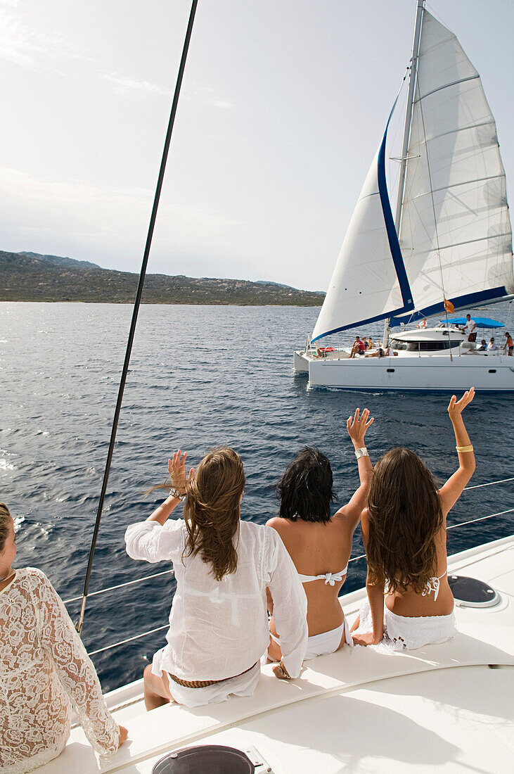 Women waving from sailboat on ocean