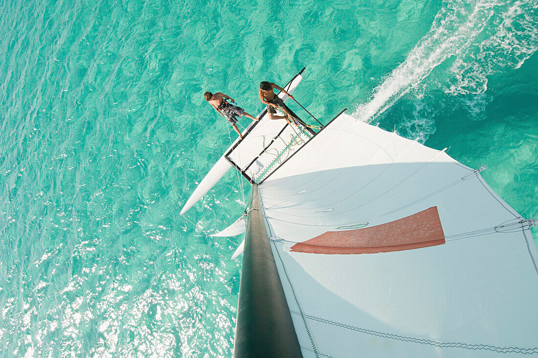 High angle view of men hoisting rigging on sailboat