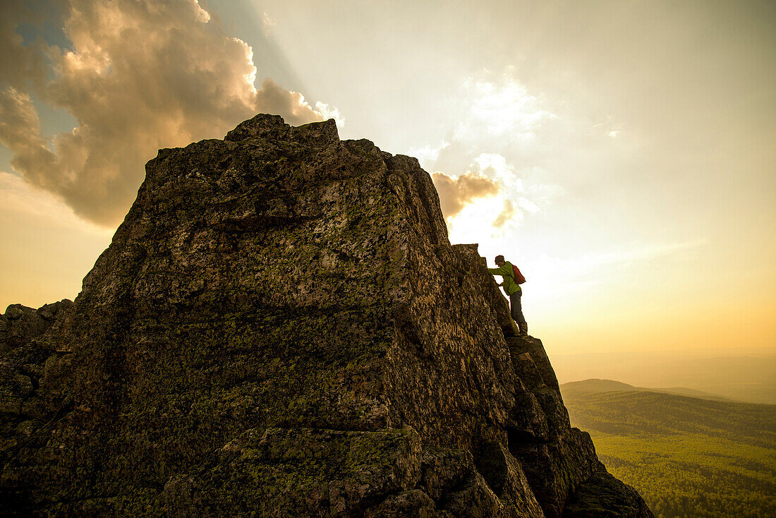 Caucasian hiker climbing on rock formation