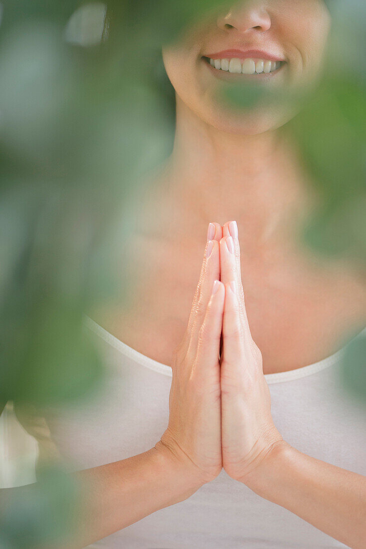 Gemischtrassige Frau meditiert mit gefalteten Händen